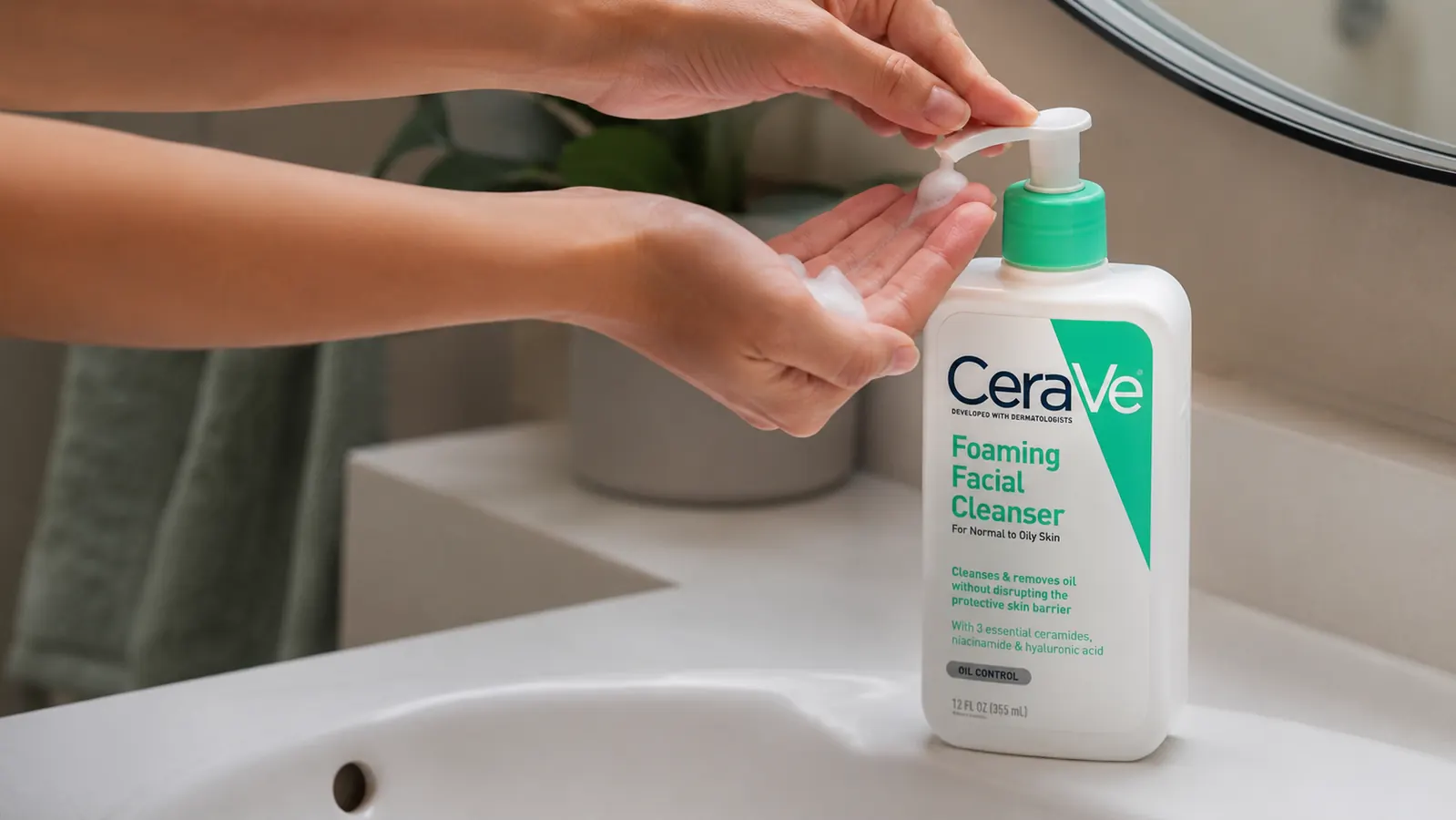 Hand dispensing a pump of foaming cleanser into a palm over a bathroom sink