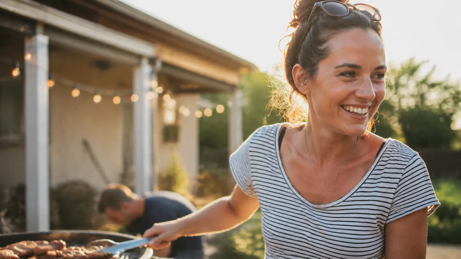 Woman in a short-sleeve shirt laughing at an outdoor summer gathering