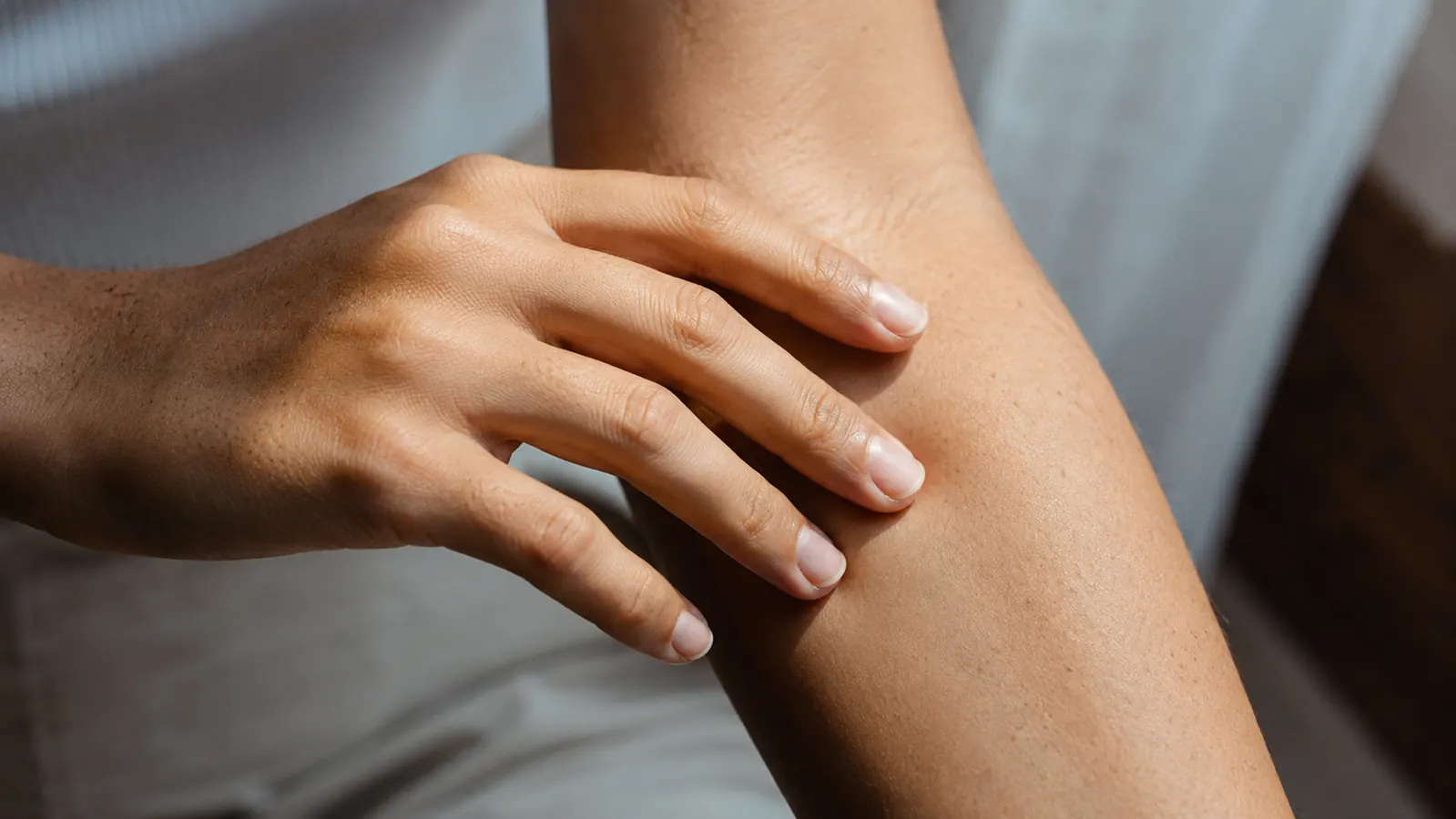 Close-up of a hand running gently over a smooth forearm in natural light